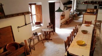 Sa Cuina dets Amos
La estancia nos lleva al recuerdo de la vida y el trabajo en el campo. Una gran chimenea con su tradicional campana de obra delimita un escalfapanxes y la puerta de un horno de leña de considerable tamaño.
Antiguamente era el espacio donde se hacía más vida: cocinar, comer, coser, pasar una velada...
Espacio multifuncional que conserva todos los detalles y en el que, a su vez, se han introducido elementos modernos necesarios para hacerlo operativo. Ideal para pequeños grupos en caso de mal tiempo o para instalar el bufet.